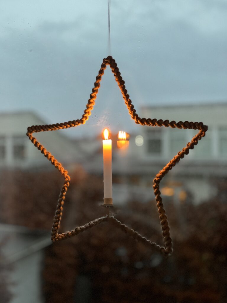 Hanging macrame star with a lighted candle