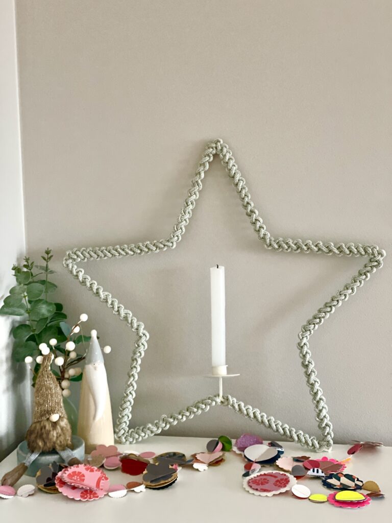 Macrame star with white candle over blank wall